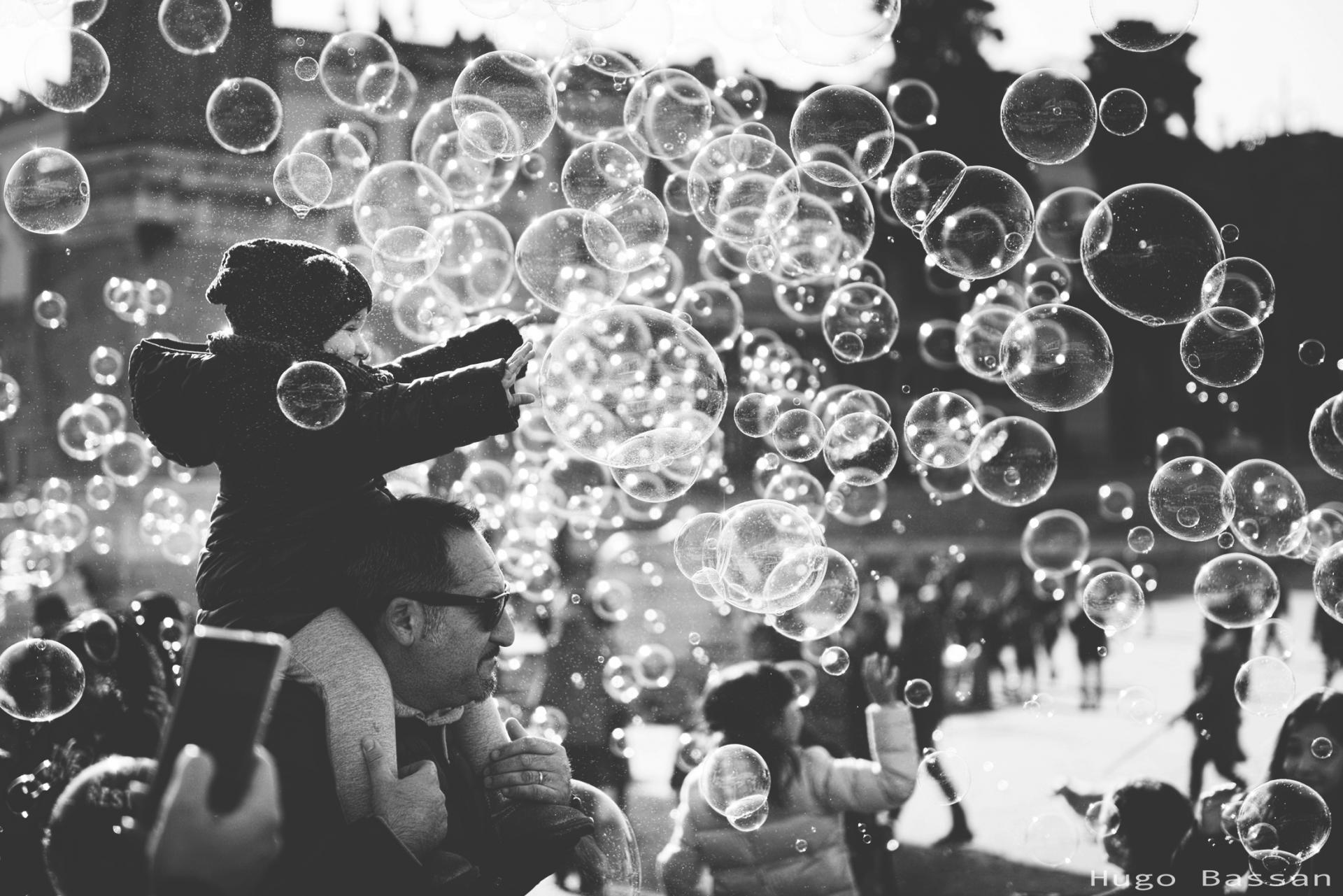 Fillette jouant avec les bulles d'un artiste de rue